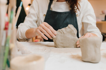Potter is sculpting wet clay for ceramics products. Hands of a female potter making ceramic clay...