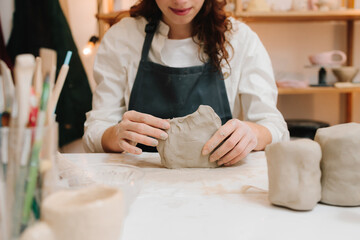 Potter is sculpting wet clay for ceramics products. Hands of a female potter making ceramic clay...