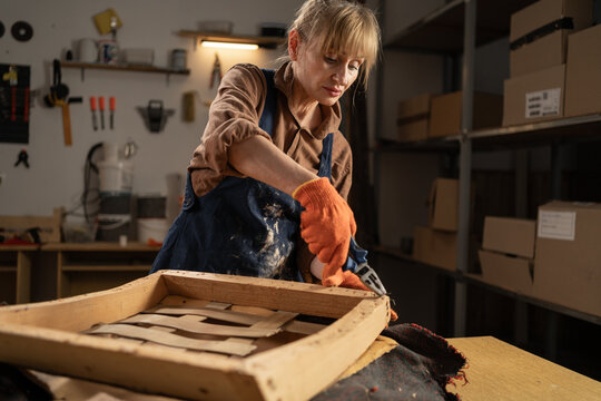 upholsterer removing antique upholstery nails. Restoration furniture