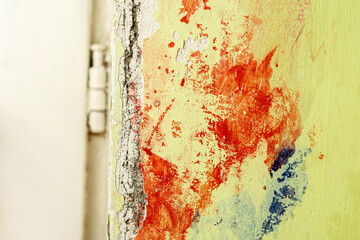 Green damaged plaster on concrete wall, old plaster needs repair. Abstract red paint strokes on...