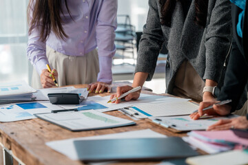 Professional women collaborating, reviewing financial data on charts and graphs, discussing...