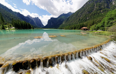 Summer scenery of Lake Dobbiaco (Toblacher See) under sunny sky with majestic mountains reflected...
