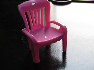 Fototapeta premium Pink plastic chair on a black background. Selective focus. Copy space.