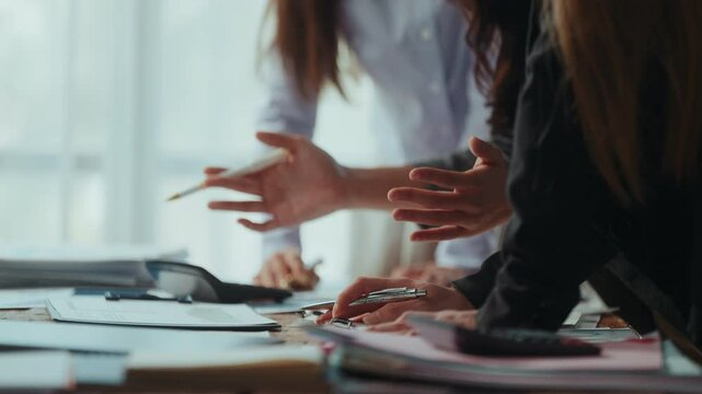 Professional women reviewing financial reports, collaborating over spreadsheets and calculating business metrics near office window - Powered by Adobe