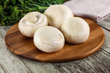 White champignon mushrooms heap over board