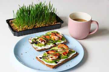 Tasty avocado shrimp toast with cream cheese and balsamic glaze on rye bread served with coffee: healthy breakfast idea, clean eating, ketogenic diet, Scandinavian food.