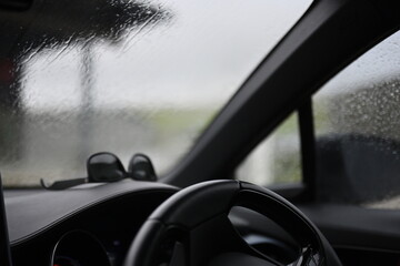 inside of car on a rainy day with steering wheel and dashboard