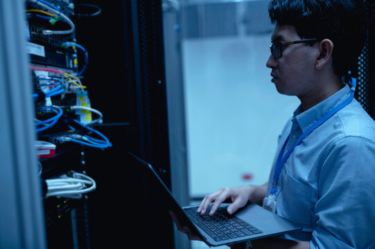 Computer engineer is setting up network in server room,Systems Maintenance Technician,Male engineer working in server room at modern data center - Powered by Adobe