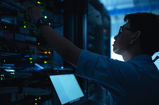 Computer engineer is setting up network in server room,Systems Maintenance Technician,Male engineer working in server room at modern data center