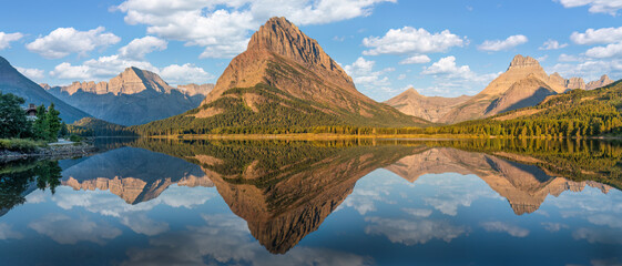 Sunrise golden light panorama from the Many Glacier Hotel - reflection on Swiftcurrent Lake of Grinnell Point - Glacier national Park