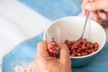 Person in the process of packing caramelized peanuts into individual bags using a spoon. Retail concept.