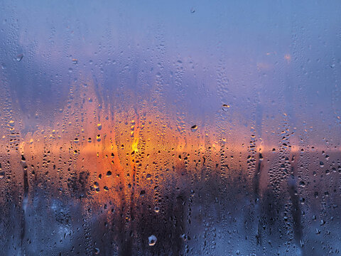 Water drops on the window at sunrise. Beautiful blurred picture of sunset through foggy glass. Abstract background. Soft focus. Artificial noise and grain - Powered by Adobe