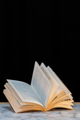 Open book with moving pages on black background on marble surface. Effect of rapidly turning pages in open book with dark background. Image with copy space
