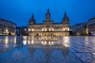 Naklejka premium Night view of Plaza María Pita in A Coruña, Galicia, with its illuminated architecture reflected on the wet ground after the rain. 