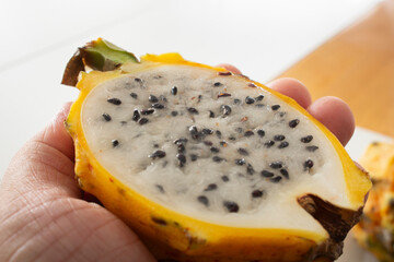 A closeup view of a hand holding a yellow dragon fruit half.