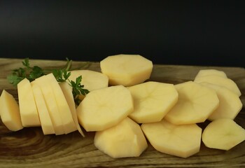 Parsley and chopped potatoes on a wooden patterned cutting board. Meal preparation.