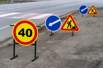 Brightly colored road signs display a speed limit of 40 and construction warnings along a busy city...