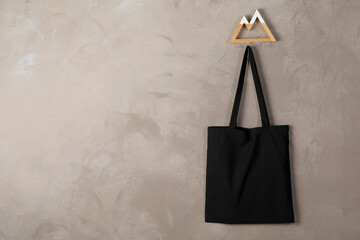 Black eco bag hanging on grey wall. Mockup for design