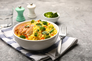 Tasty rice with vegetables and chicken served on grey table, closeup