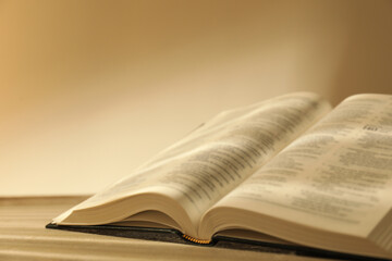 Open Holy Bible in English language on beige table, closeup