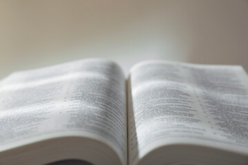 Fototapeta premium Open Holy Bible in English language against beige background, closeup