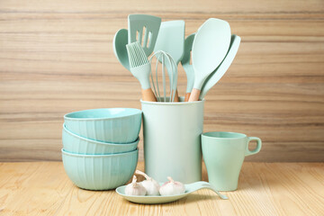 Dishware, cooking utensils and garlic on wooden table