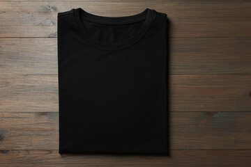 Blank black t-shirt on wooden background, top view. Mockup for design