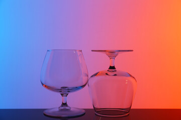 Empty glasses on table against color background