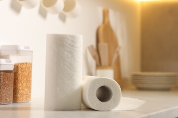 Rolls of paper towels on white countertop in kitchen, space for text
