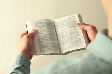 Fototapeta premium Man reading Holy Bible in English language on light background, closeup