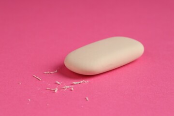 One eraser and scraps on pink background, closeup