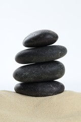 Stack of rocks on sand against white background. Harmony and life balance