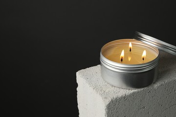 Burning soy wax candle and lid on concrete block against gray background, space for text