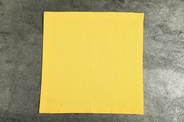 Yellow napkin on grey table, top view