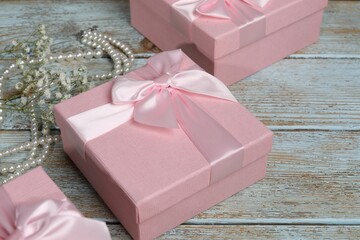 Beautiful wedding gifts, pearl jewelry and gypsophila flowers on wooden table, closeup