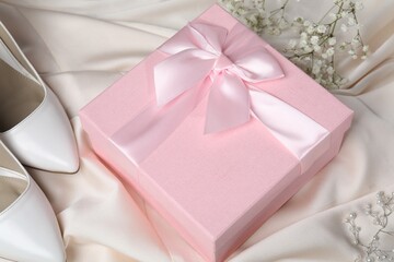 Beautiful wedding gift, pearl jewelry, bridal shoes and gypsophila flowers on beige silk fabric, closeup