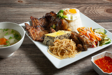 A view of a Vietnamese entree called com tam dac biet, consisting of pork chop and broken rice.