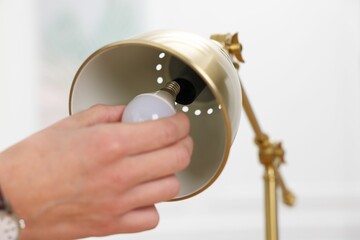 Man changing light bulb in lamp at home, closeup. Space for text