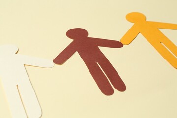 Stop racism. Paper human figures of different colors on beige background, closeup