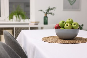 Bowl of apples on table with white tablecloth indoors