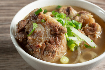 A closeup view of a small bowl of oxtail in broth.