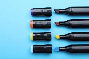 Colorful markers on light blue background, flat lay