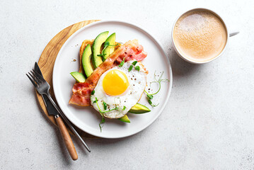 Breakfast toast with fried egg, bacon and avocado