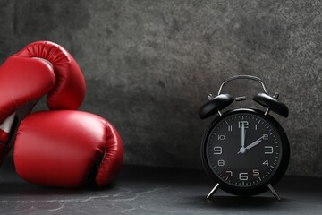 Alarm clock and boxing gloves on grey background