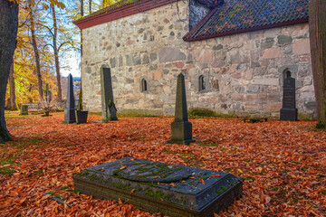 View of the 11th century Nidaros Cathedral cemetery in autumn with red and golden foliage in Trondheim, Norway