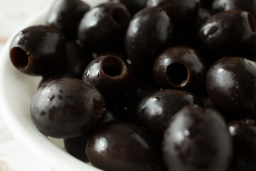 A closeup view of a bowl of canned pitted black olives.