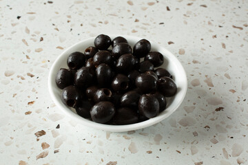 A view of a bowl of canned pitted black olives.