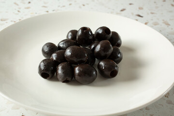 A view of a pile of black olives, on a plate.