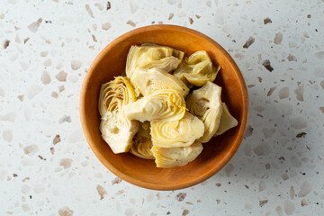 A top down view of a bowl of marinated artichoke heart quarters.