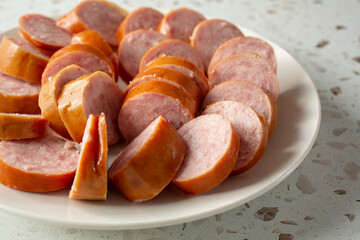 A closeup of a plate of par-cooked kielbasa slices.